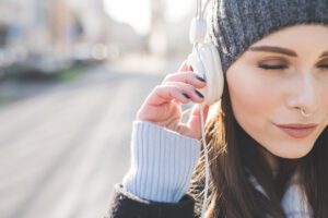 A portrait of a young, beautiful Caucasian pierced woman with Septum Piercing and listening to music with headphones.